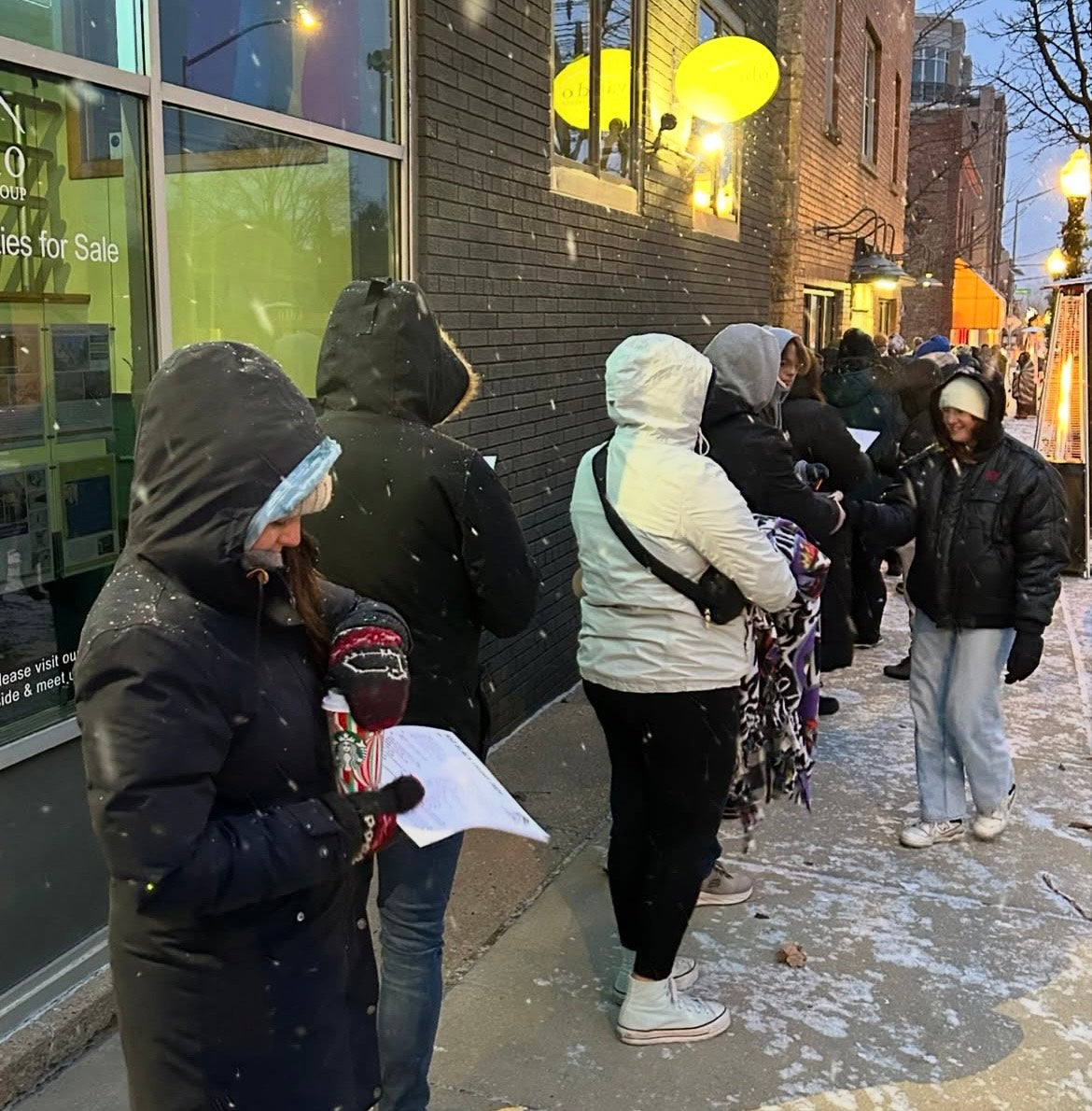People waiting in line outside a building on a snowy day